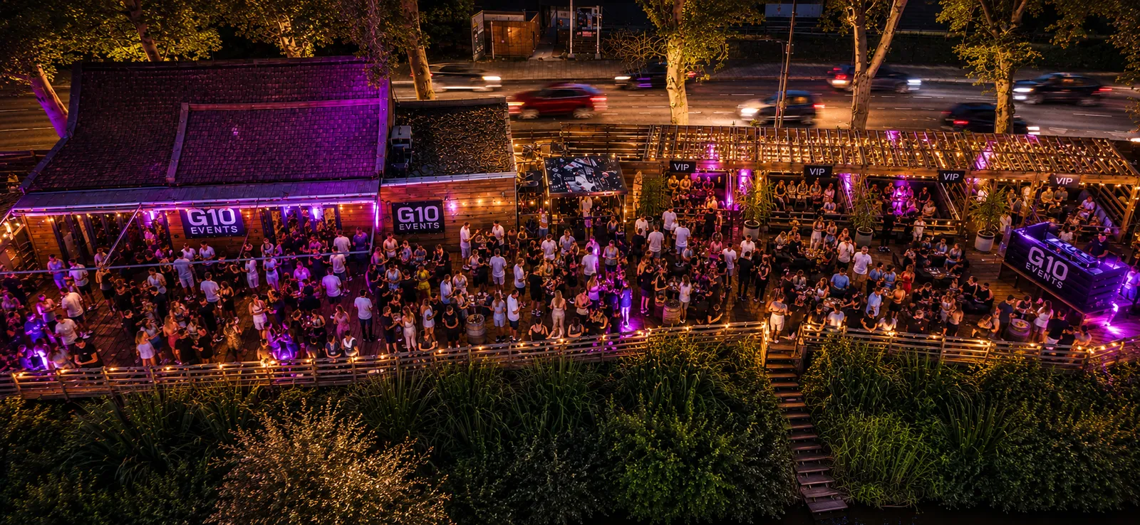 Riverside music venue at night with open-air decking, illustrating the Party by the River setting.